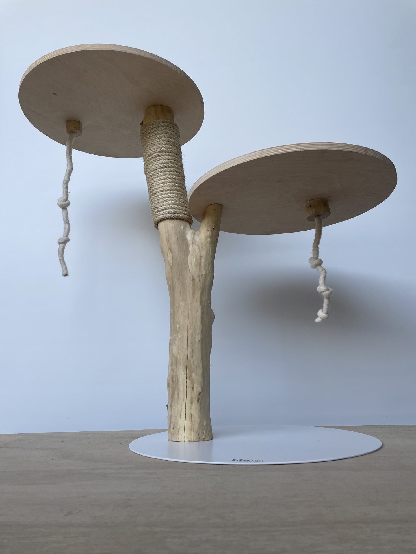Puristischer Naturkratzbaum ohne Fellbezug. Zwei Ebenen aus hochwertigem Holz auf einer stabilen, weißen Metallplatte – modernes Design trifft Natur.