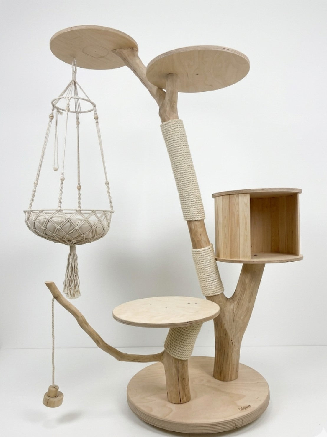 Moderner Naturkratzbaum der Katzbaum-Manufaktur mit integrierter Kuschelhöhle, hängender Spielschaukel und drei runden Echtholz-Liegeflächen auf einer stabilen weißen Metallbodenplatte.